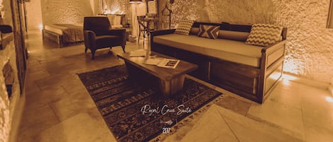 Una sala de estar acogedora con sofá, sillón y mesa de centro, que destaca por una pared de piedra rústica y un tapete estampado.
