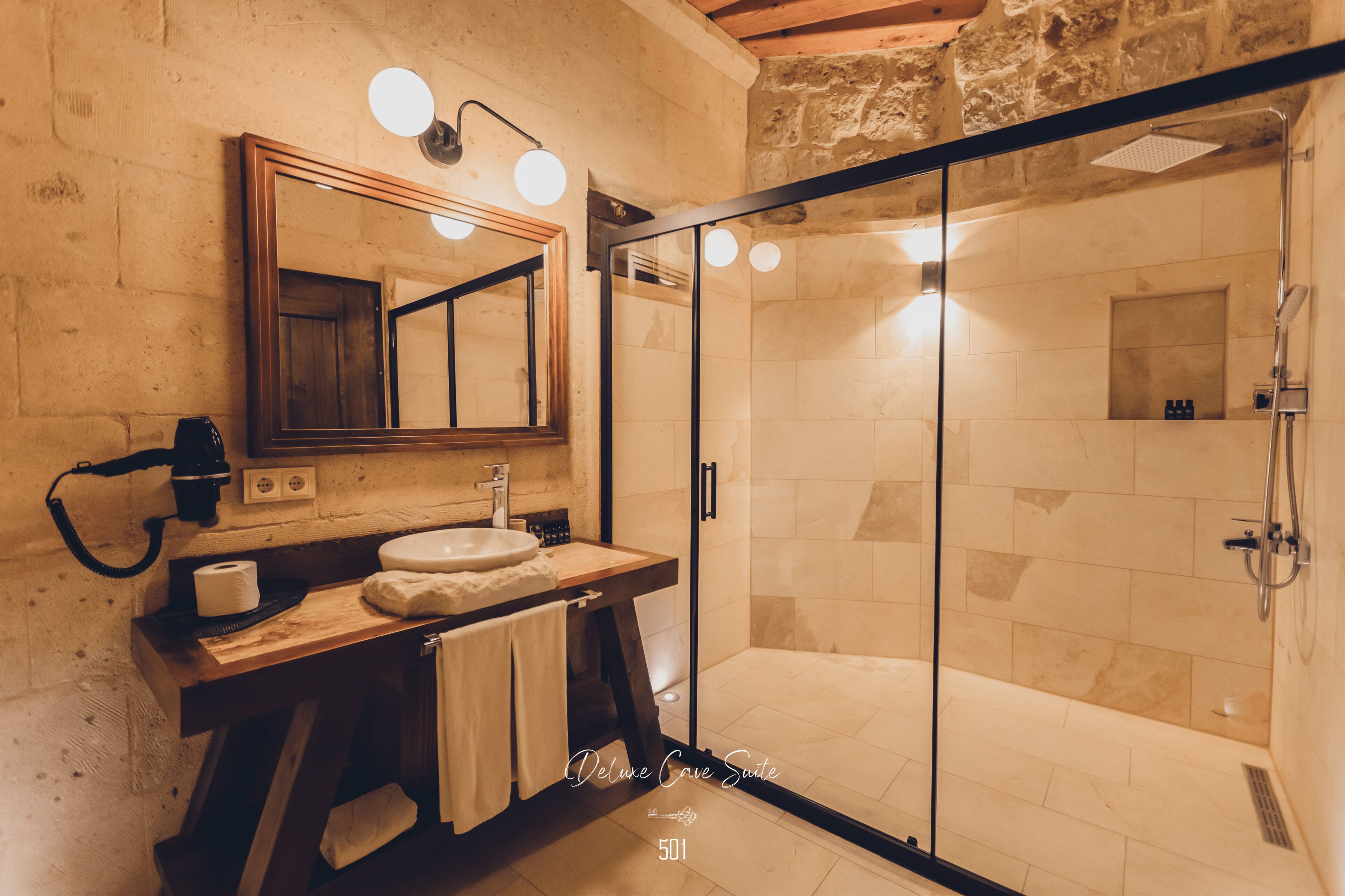 A modern bathroom with a glass-enclosed shower, a wooden vanity, and a large mirror.