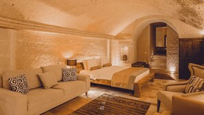 Un dormitorio acogedor con una cama grande, un sofá y una silla, que destaca por su techo texturizado y una pared de piedra.