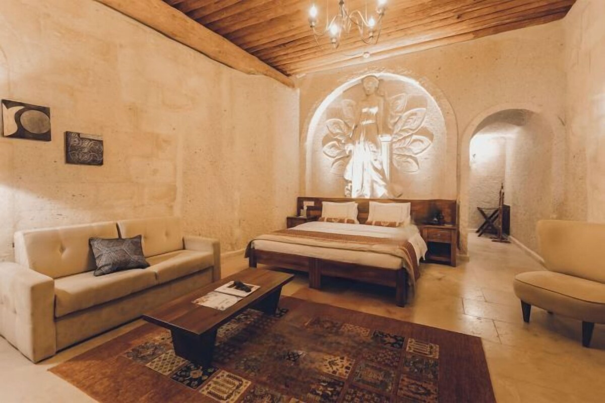 A bedroom with a large bed, a sofa, a coffee table, and a chandelier.