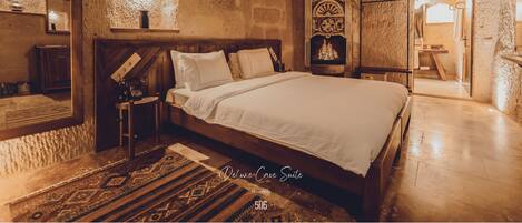 A cozy, rustic bedroom with a large bed, wooden headboard, and a decorative mirror.