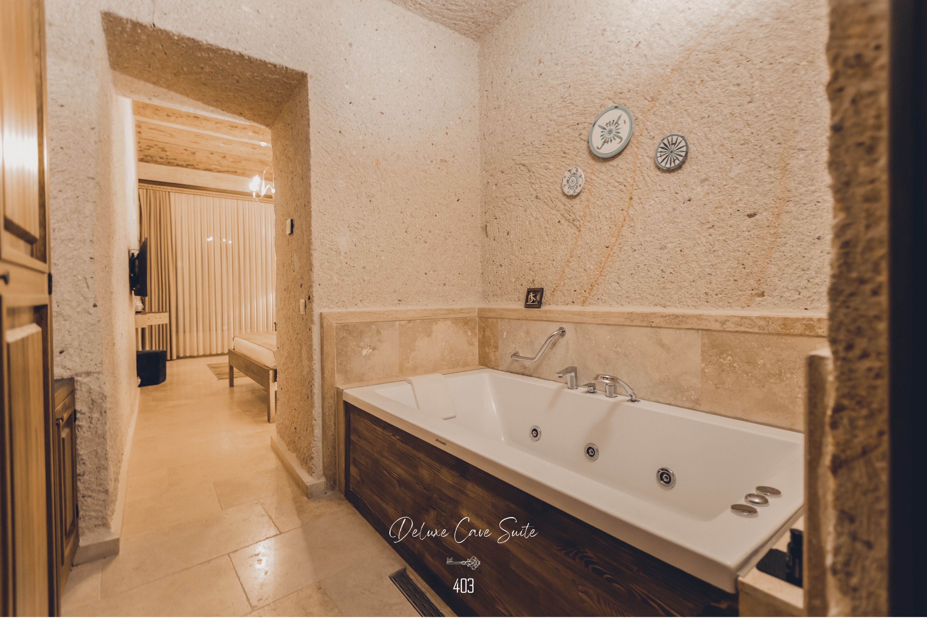 A bathroom with a large bathtub, a bench, and a towel rack.