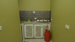 Uma cozinha pequena com fogão a gás, armários e um cilindro de gás vermelho.