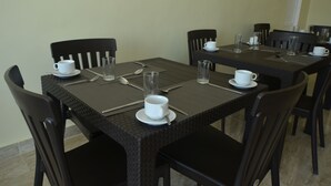 Uma área de refeições com uma mesa posta para quatro pessoas, incluindo xícaras brancas, talheres e um copo.
