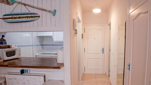 A kitchen with a microwave, a sink, and a broom hanging above it. There is a door leading to another room. - Las Vistas Beach 2 minutes to the Beach (Arona)