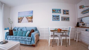 A cozy living area with a sofa, a dining table, and chairs. There are framed pictures on the wall and a kitchen area with a microwave. - Las Vistas Beach 2 minutes to the Beach (Arona)