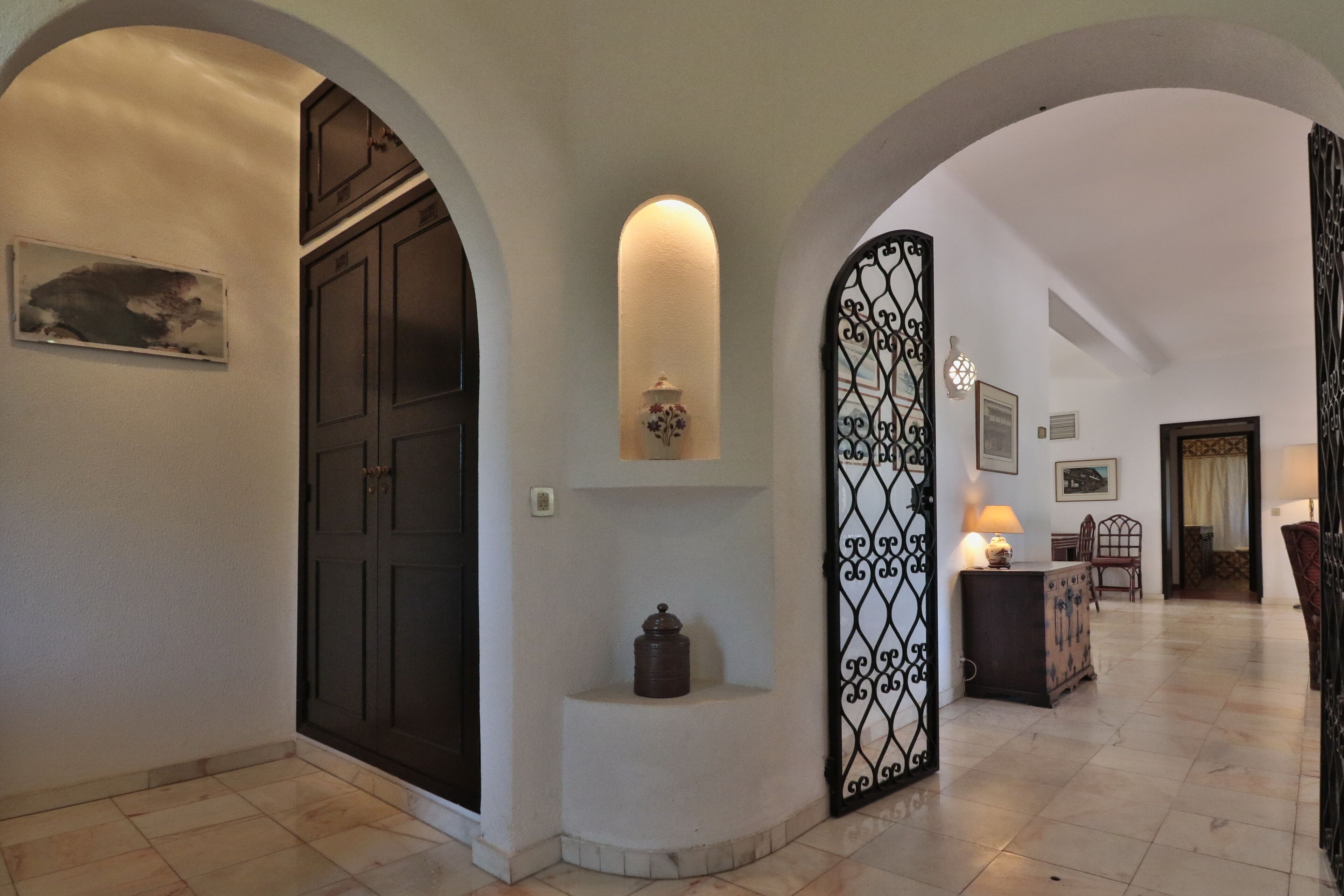 A hallway with a dark wooden door, a decorative wall-mounted light, and a patterned metal partition.