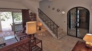 Ein geräumiger Wohnbereich mit Treppe, einer Couch, einem Tisch und einer Lampe.