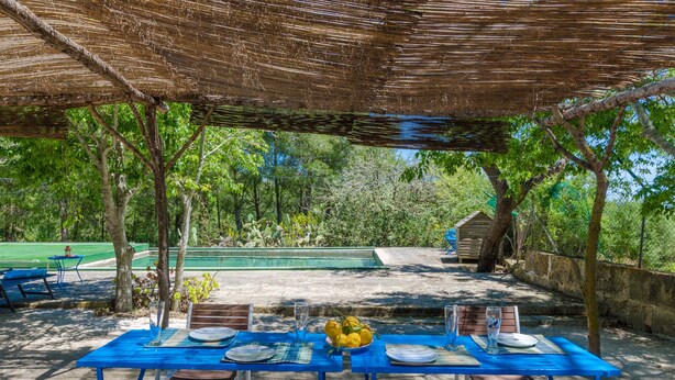 An outdoor dining area with a table set for four, surrounded by wooden chairs.