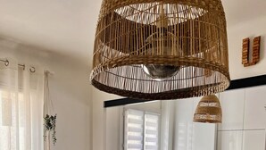 Uma cozinha moderna com ilha central, banquetas, máquina de café e luminária de vime suspensa.