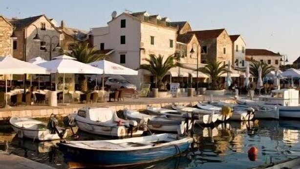 A marina with boats docked, stone buildings, and outdoor seating areas. - Luxurious Penthouse with Wonderful Sea and Old Town View (Primosten)