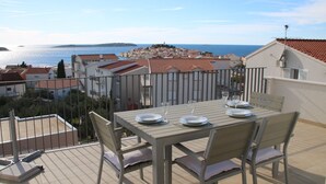 A terrace with a table set for two, overlooking a coastal town. - Luxurious Penthouse with Wonderful Sea and Old Town View (Primosten)