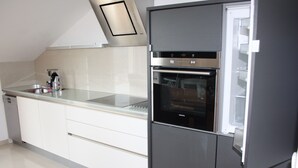 A modern kitchen with a built-in oven, a stainless steel refrigerator, and a glass countertop. - Luxurious Penthouse with Wonderful Sea and Old Town View (Primosten)