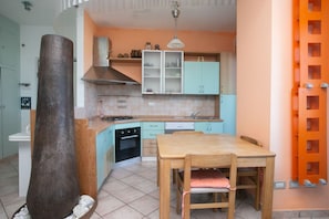A kitchen with teal cabinets, a wooden table, and a large vase.