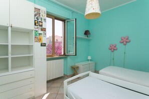 A bedroom with a bed, a dresser, a window, and a radiator.