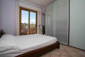 Un dormitorio con una cama, un ventanal corredero y vistas a una valla roja.