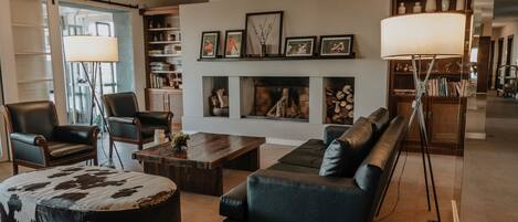 Una sala de estar moderna con mobiliario de cuero, chimenea, estanterías y un ventanal grande.