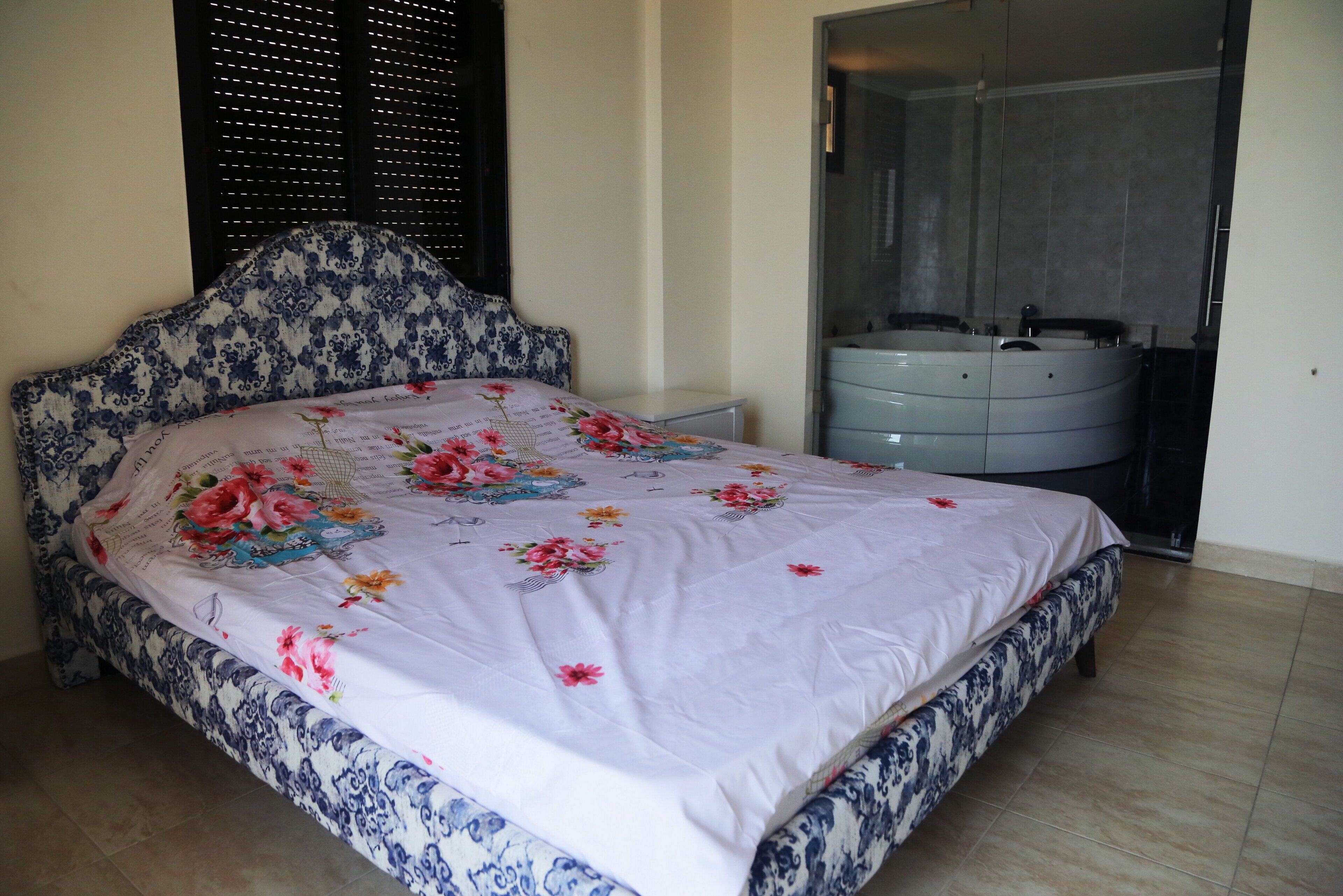 A bedroom with a bed, a nightstand, a dresser, and a bathroom with a bathtub.