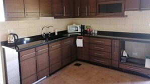 Una cocina con armarios de madera oscura, encimera negra y microondas.