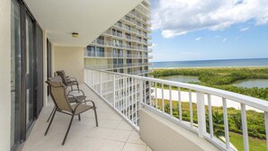 A balcony with chairs, a view of the sea, and a building with multiple floors. - Beachfront 2BR/2BA condo with pool, Wi-Fi, and beach access. (Marco Island)