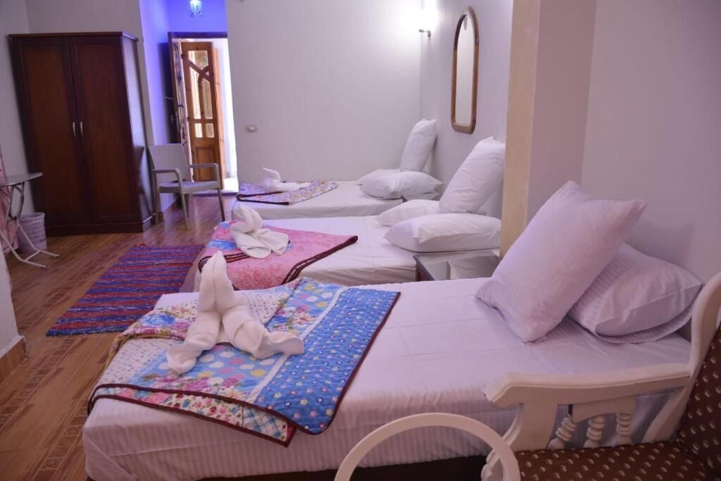Une chambre d’hôtel avec deux lits, une armoire, une chaise et une petite table.
