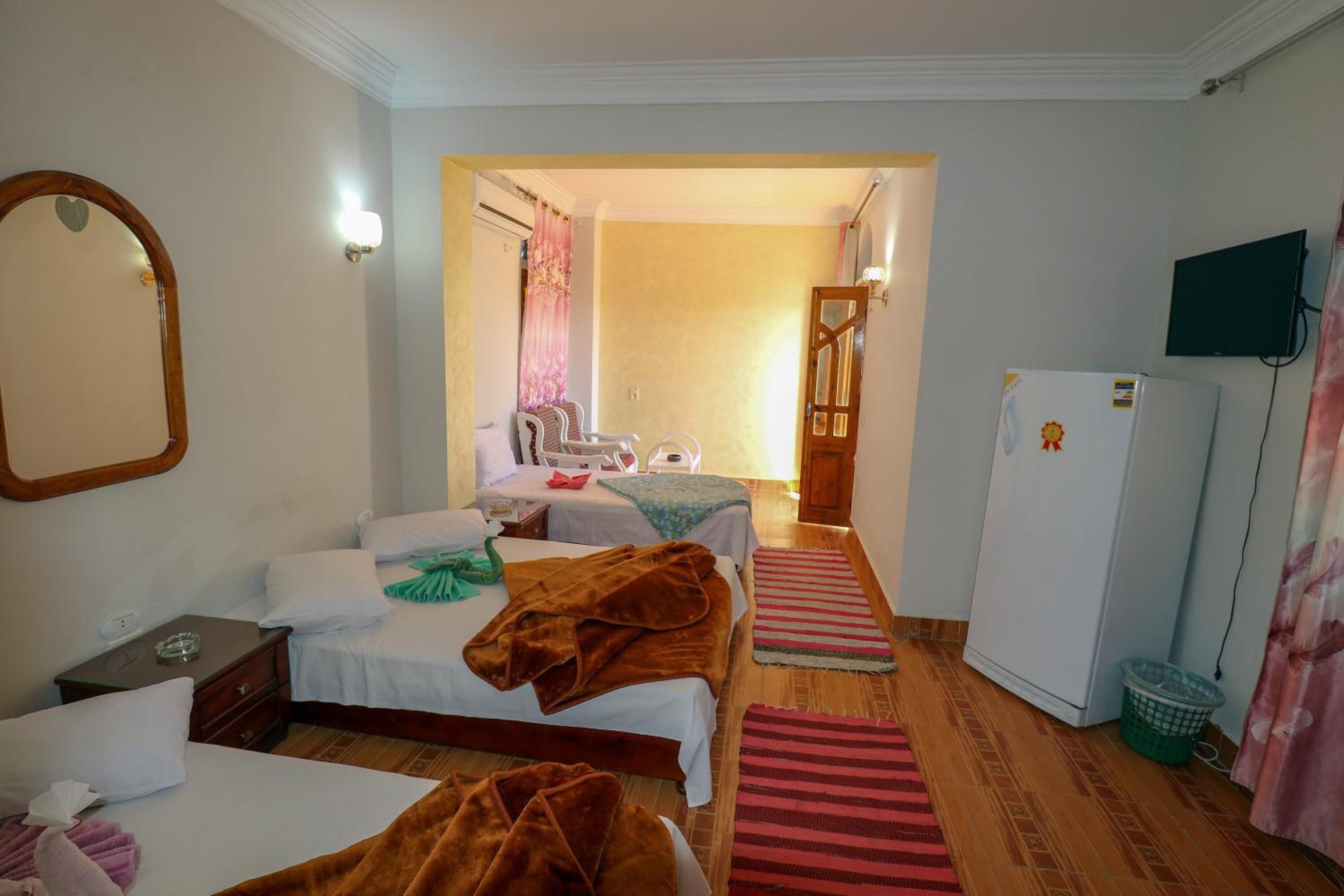 A hotel room with two beds, a television, a refrigerator, and a bathroom visible through an open door.