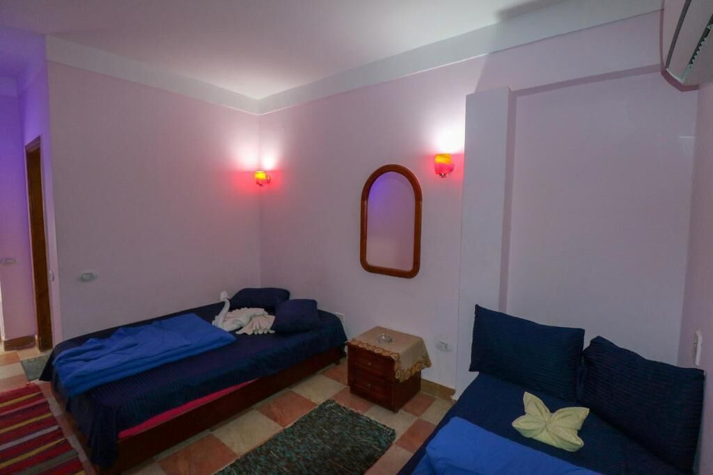 Ein Schlafzimmer mit zwei Betten, einem Spiegel und Wandleuchten.