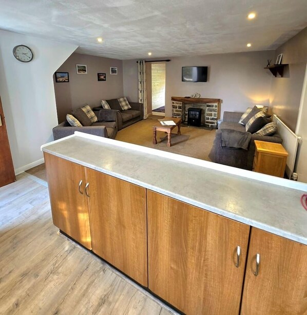 A living room with a sofa, a coffee table, a fireplace, and a TV mounted on the wall.