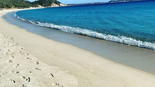 Ein Strand mit klarem, blauem Wasser und einem Sandufer.