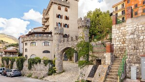 A castle-like building with stone walls, a tower, and a staircase leading up to a gated entrance. - Hotel Castello di Giuliano (Montelepre)