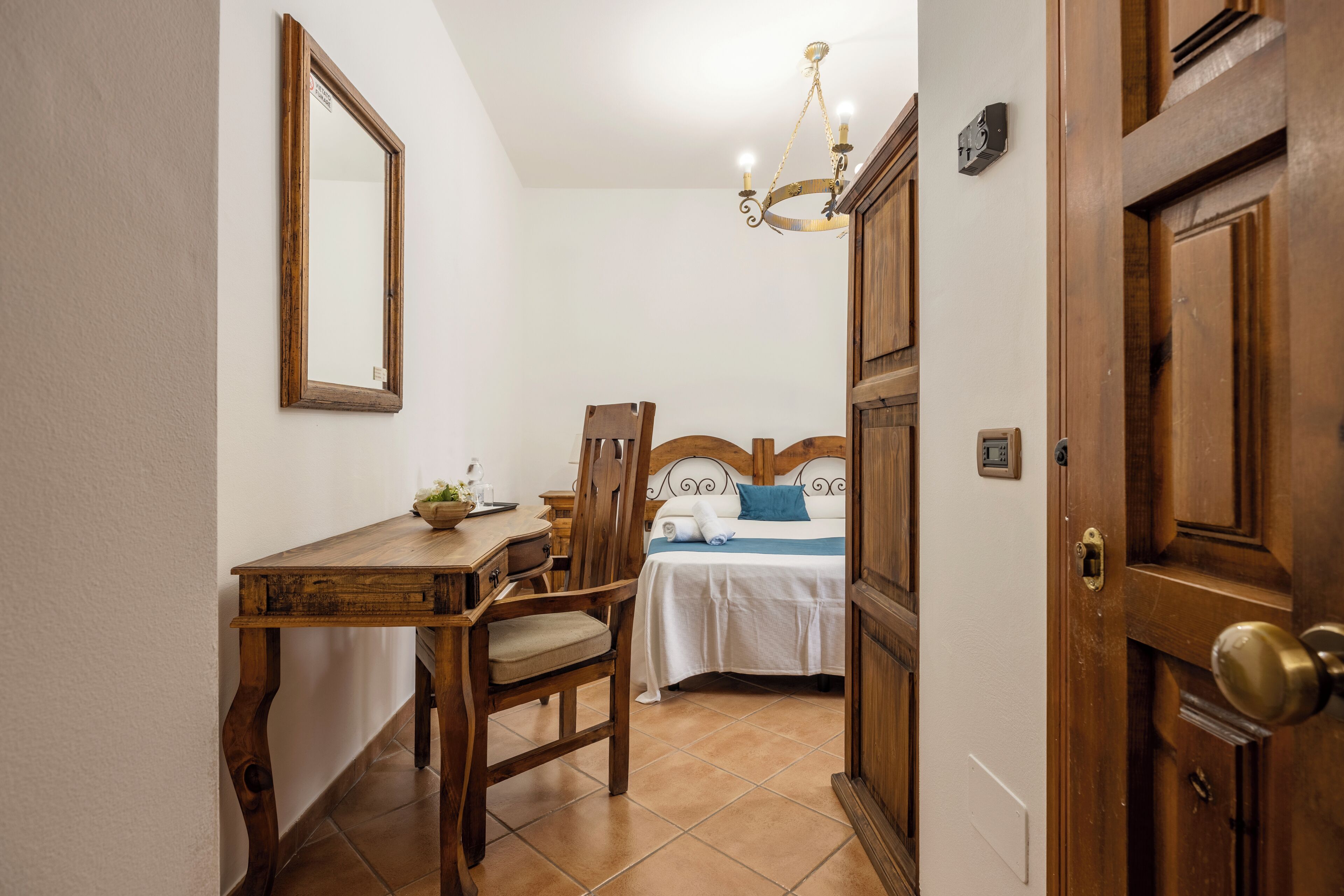 Un dormitorio con una cama de madera, una mesita de noche, una silla, un escritorio y un espejo.