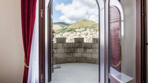 An open archway leading to a balcony with a view of a cityscape and a hill. - Hotel Castello di Giuliano (Montelepre)