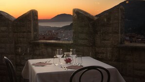A table set for two with a view of a city and mountains at sunset. - Hotel Castello di Giuliano (Montelepre)