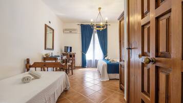 Une chambre d’hôtel avec deux lits, un bureau, une chaise, une télévision et une porte en bois.