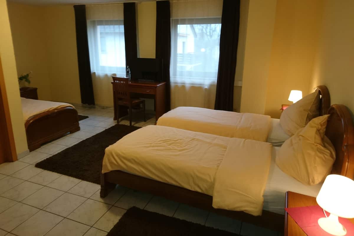 A hotel room with two beds, a desk, and a chair.