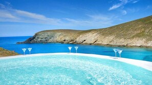 Un bain à remous offrant une vue dégagée sur l’océan et une colline rocheuse en arrière-plan.