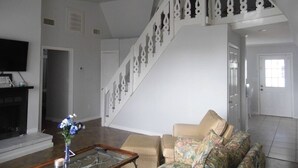 Un salon comprenant un canapé, une table basse, une cheminée et un escalier agrémenté de rampes décoratives.