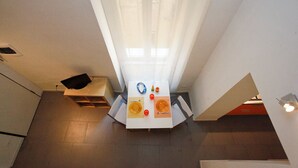 Une cuisine moderne avec un coin repas, comprenant une table blanche mise avec des assiettes, un couteau et une bouteille.
