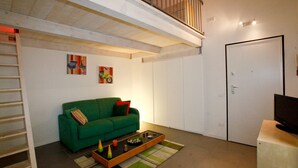 Un salon moderne avec un canapé vert, une table basse et des œuvres d’art accrochées aux murs.