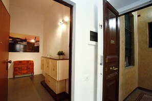Un passadís amb un armari de fusta, un quadre amb marc a la paret i una porta amb mànec metàl·lic.