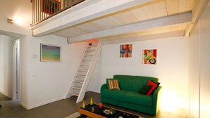 Un salon avec un canapé vert, une table basse et un escalier.