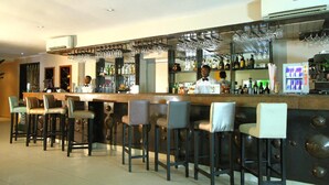 A bar area with multiple stools, a bartender, and a well-stocked bar counter. - La Cour Hotel Apartments (Lagos)