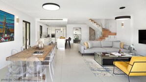 Ett modernt vardagsrum med matplats, soffa och trappa.
