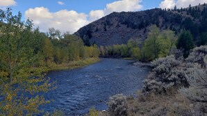 Ein Fluss fließt durch ein bewaldetes Tal, im Hintergrund erhebt sich ein Berg.