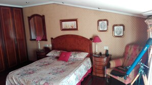 Una camera da letto con un letto, comodini, una sedia e quadri appesi alle pareti.