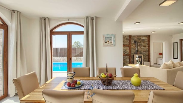 A dining area with a view of a swimming pool, a fireplace, and a living room with a sofa and a lamp. - Charming 3-BR villa with private pool close to beaches (Novigrad)