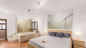 Een moderne hotelkamer met een groot bed, een aparte badkamer met bad en een groot raam.