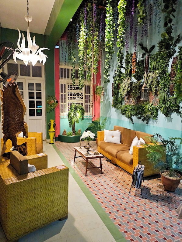 Relax in a serene space with a comfortable sofa, wicker furniture, and lush greenery.