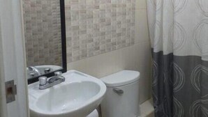 Un bany amb un rentamans blanc, un vàter i una cortina de dutxa.