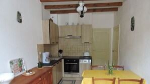Una cucina compatta con mobili in legno, un piano cottura, un lavello e un tavolo da pranzo con sedie.